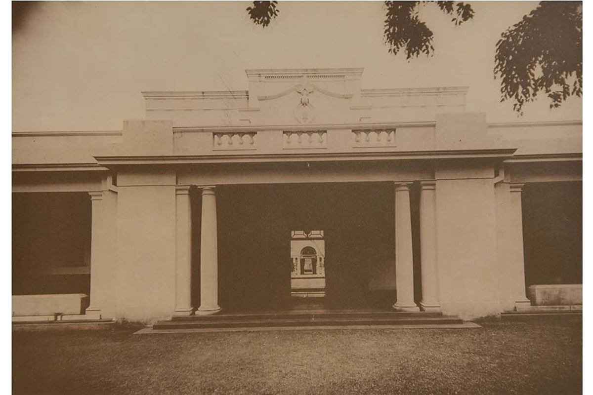An archival sepia photograph of the hotel's original colonnaded entrance.