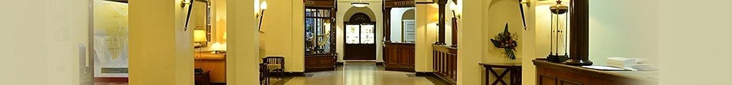 A wide view along the hotel's interior corridor, with lamps, arches and polished floors.